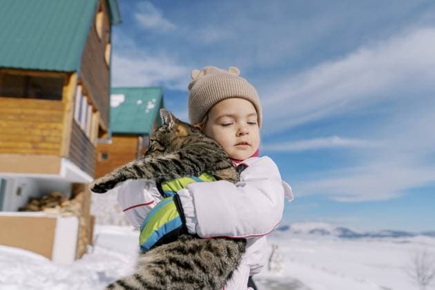 Creative Highlight Symbolbilder Kleines Mädchen umarmt eine getigerte Katze, während sie im Schnee in der Nähe einer Holzhütte steht Little girl hugs a tabby cat while standing in the snow near a wooden cottage. Copyright: imageBROKER NadtochiyxVladimir ibxiqx13182393.jpg ,model released, Symbolfoto ,property released