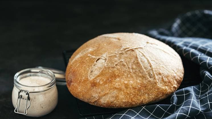 Weizen runden Sauerteig Brot und Sauerteig Starter in Glas jar.Side Ansicht von hausgemachten Sauerteig Brot auf schwarzem Hintergrund mit Kopie Raum. Lange horizontale banner.Home gemacht Sauerteig Brot machen Konzept Wheat round sourdough bread and sourdoug starter in glass jar.Side view of homemade sourdough bread on black background with copy space. Long horizontal banner.Home made sourdough bread making concept Copyright: imageBROKER OlgaxSergeeva ibxiqx13219777.jpg