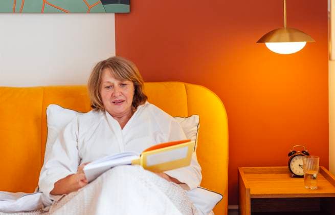 Eine ältere Frau in einem weißen Kittel liest im Bett, bevor sie zu Bett geht. Eine schöne Frau mittleren Alters lächelt und hält ein Buch in der Hand. Ein Rentner entspannt sich zu Hause. An elderly woman in a white coat reads in bed before going to bed. A beautiful middle-aged lady is smiling and holding a book. A pensioner relaxes at home. Stylish, cozy, modern interior of the house (License=RF) ,model released, Symbolfoto Copyright: xZoonar.com DashaxPetrenkox 23406260 ,model released, Symbolfoto ,property released