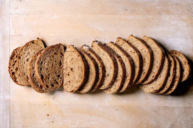 Geschnittenes Handwerks-Sauerteigbrot Laib Freshly baked artisan sourdough bread sliced into portions on wooden background. Crusty rustic loaf with airy texture shows natural fermentation pattern. (License=RF) Copyright: xZoonar.com NATASHAxBREENx 23411760