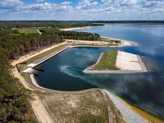 Sportboothafen Teichland am Ostsee DEU Brandenburg Neuendorf Â Sportboothafen Teichland: Bereits im Jahr 2022 wurde das Hafenbecken aus dem Ufer des Ostsees geformt. Es soll wie eine natürliche Einbuchtung wirken, geschützt von einer vorgelagerten Insel, die vor allem Wind- und Wellenschutz für die gut 100 Boote dient, die künftig im Hafen liegen können. Das Land stellte für Böschungsbefestigungen und Slipanlage mit entsprechender Kranaufstellfläche Fördermittel von 7,3 Millionen zur Verfügung. Der Ostsee hat sich im Jahr 2025 bereits den geplanten Füllstand erreicht und der einstige Tagebau Cottbus-Nord und verwandelt sich damit bis an den Horizont in den größten künstlichen See Deutschlands. Nach dem Ende 2015 die K