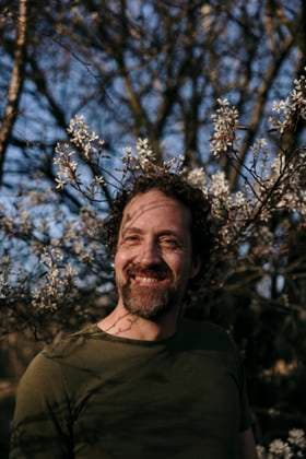 IMAGO Creative, Ostern, Bräuche, Osterspaziergang #2 Smiling man outdoors near blooming tree in warm sunlight Amsterdam, North Holland, Netherlands CR_RTBZ250515-1731110-01 ,model released, Symbolfoto