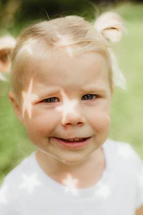 Creative Highlights Symbolbilder Smiling girl with star-shaped shadows on face in sunny field. Concordia, Kansas, United States R_ZMDZ250515-1730561-01 ,model released, Symbolfoto