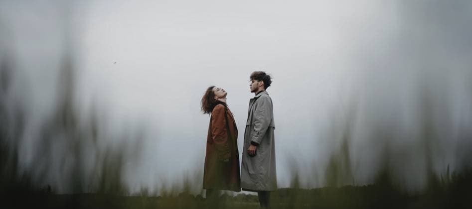 Creative Highlights Symbolbilder Ein Paar, das in einem Feld steht und nach oben schaut, in langen Mänteln und mit einem Gefühl der Verbundenheit A couple standing in a field, each looking upwards, dressed in long coats with a sense of connection Copyright: imageBROKER MikalaixSayevich ibxwsp12689754.jpg ,model released, Symbolfoto ,property released