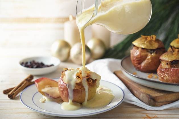 Vanillesoße auf einen mit Mandeln, Honig und Rosinen gefüllten Bratapfel gießen, hausgemachtes Winterdessert für Feiertage wie Weihnachten, Thanksgiving oder Neujahr, Kopierraum, ausgewählter Fokus Pouring vanilla sauce on a baked apple filled with almonds, honey and raisins, homemade winter dessert for holidays like Christmas, Thanksgiving or new year, copy space, selected focus Copyright: imageBROKER MarenxWinter ibxiqx11195460.jpg