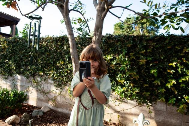 Creative Highlights Symbolbilder Little girl smiling and looking at phone Surprise, Arizona, United States R_TTIF250520-1726919-01 ,model released, Symbolfoto
