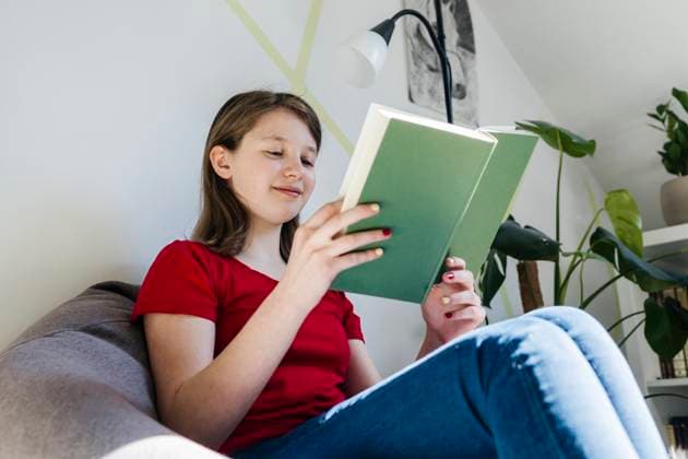 Teen reading a book in a cozy room with a dog nearby model released, Symbolfoto property released, ELMF01118