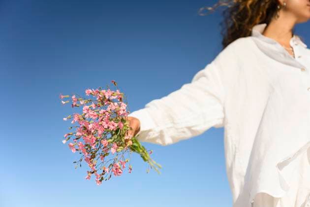 Creative Highlights Symbolbilder Young woman holding flowers against a clear blue sky model released, Symbolfoto property released, FLMZF00517