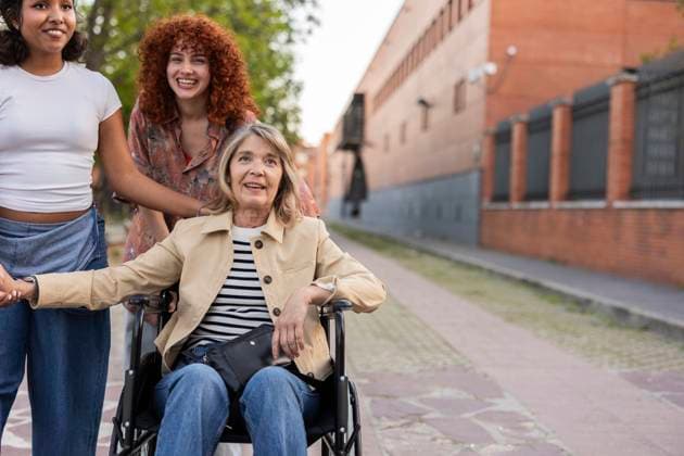 Mother in a wheelchair with two young women outdoors showing togetherness and support model released, Symbolfoto, JCCMF13474