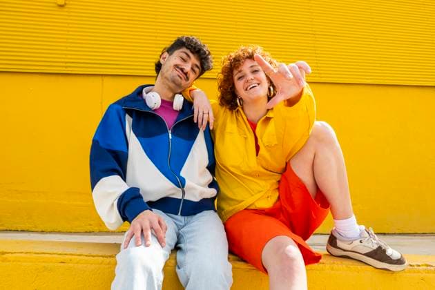 Creative Highlights Symbolbilder Friends sitting against a yellow background wearing urban clothing and smiling at the camera model released, Symbolfoto, LMCF02357