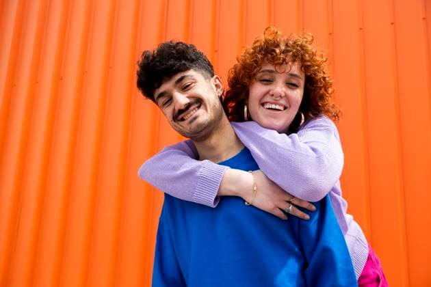 Creative Highlights Symbolbilder Young friends smiling and hugging in front of an orange background model released, Symbolfoto, LMCF02411
