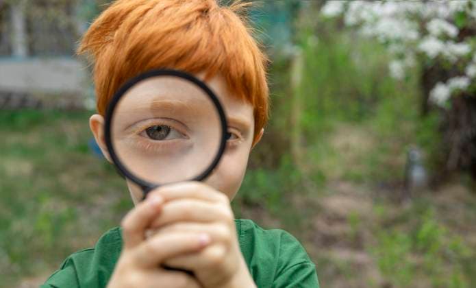 Creative Highlights Symbolbilder Boy with red hair looking through a magnifying glass in a garden model released, Symbolfoto, MBLF00825
