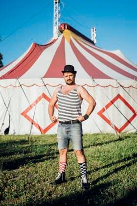 Creative Highlights Symbolbilder Muscular artist showing muscles while standing in front of circus tent model released, Symbolfoto property released, MEUF03874