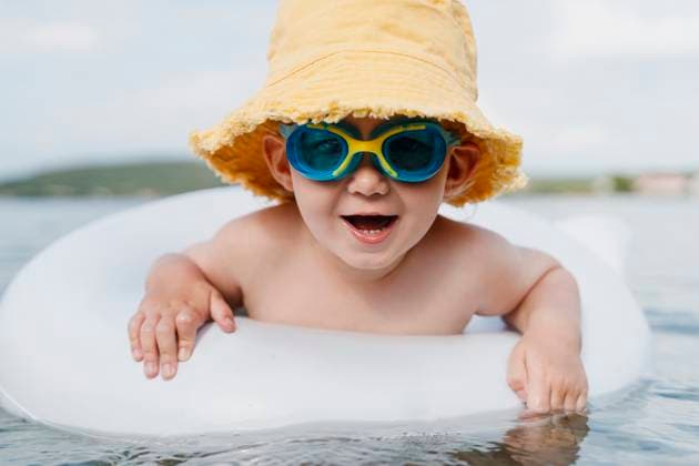 Creative Highlights Symbolbilder Boy with yellow hat and blue sunglasses enjoying summer vacation in the sea model released, Symbolfoto, NDEF02280