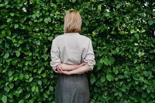 Creative Highlights Symbolbilder Woman standing against a wall of green leaves, symbolizing mental health and work-life balance model released, Symbolfoto, NDEF02311