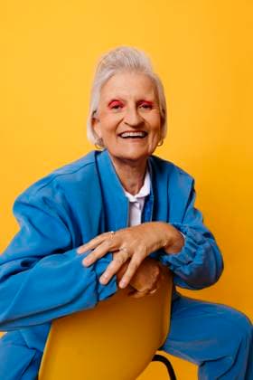 Creative Highlights Symbolbilder Smiling woman in blue jacket posing against a yellow background model released, Symbolfoto, TCEF02373