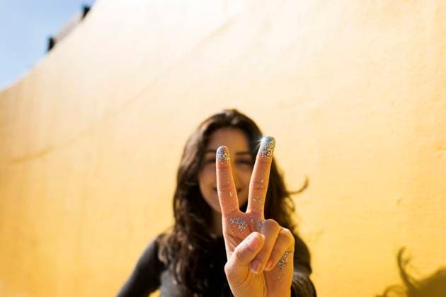 Creative Highlights Symbolbilder Woman with glitter on fingers gesturing peace sign in front of wall model released, Symbolfoto, Barcelona Barcelona Spain VABF04380