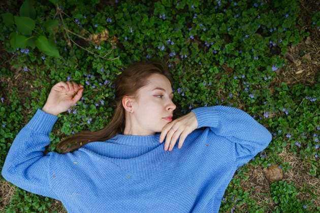 Creative Highlights Symbolbilder Woman in blue sweater lying on grass surrounded by flowers outdoors model released, Symbolfoto, VCF00730