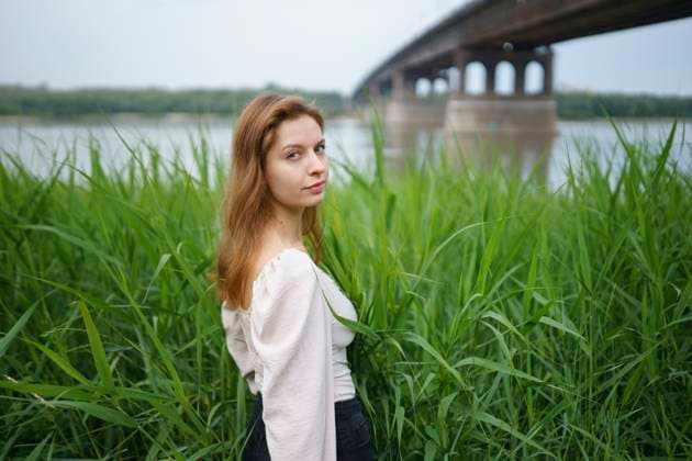 Creative Highlights Symbolbilder Woman standing on an embankment under a bridge surrounded by tall grass model released, Symbolfoto, VCF00735