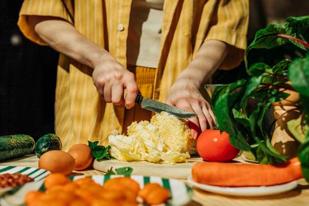 Creative Highlights Symbolbilder Woman preparing a healthy summer salad with fresh vegetables indoors model released, Symbolfoto property released, VSNF03090