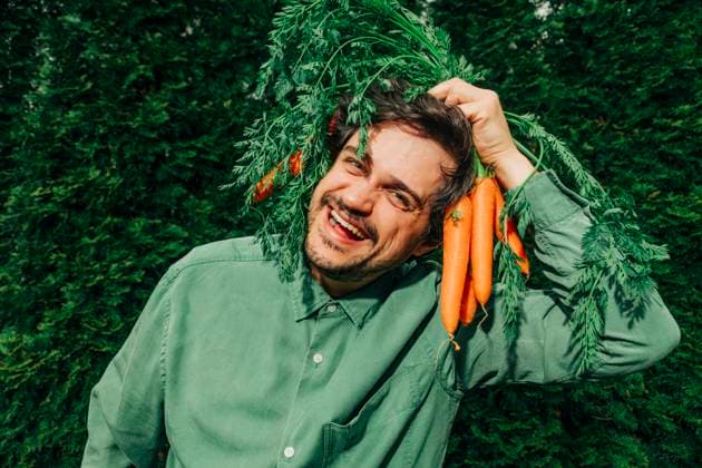 Creative Highlights Symbolbilder Man in green shirt holding carrots over his head and smiling outdoors model released, Symbolfoto, VSNF03226