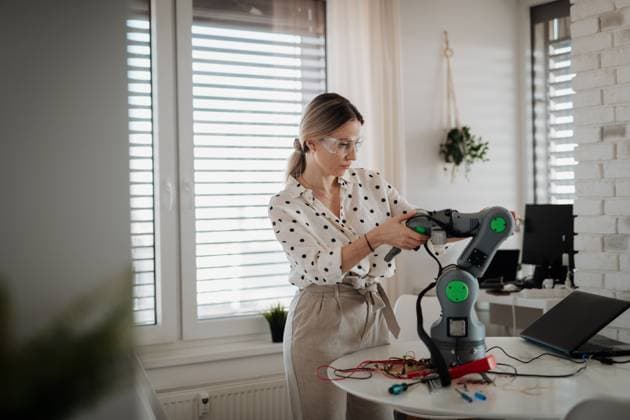 Woman engineer working on robotic arm project at home. Woman engineer working on robotic arm project at home as part of STEM activity. model released