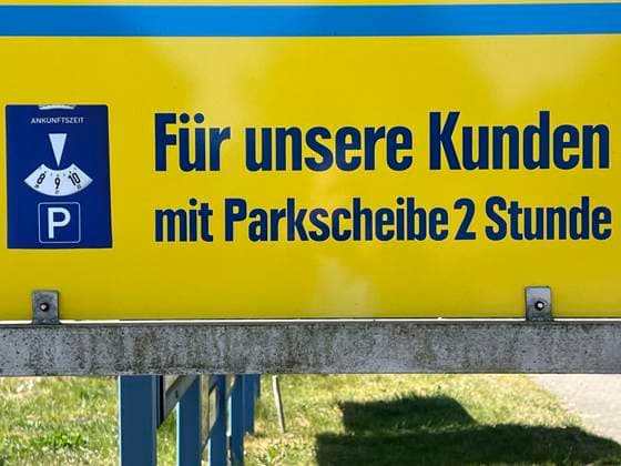 Gelb Blaues Hinweisschild auf das Parken mit dem PKW von 2 Stunden erlaubt mit einer Parkscheibe vor einem Supermarkt Mecklenburg-Vorpommern Deutschland *** Yellow Blue sign indicating that parking by car is permitted for 2 hours with a parking disk in front of a supermarket Mecklenburg-Vorpommern Germany