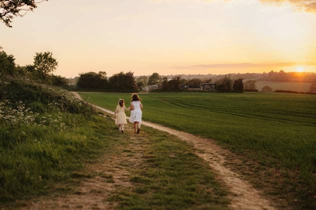 Little girls walking along green field at sunset holding hands. Corby, England, United Kingdom CR_JNDO250602-1745313-01 ,model released, Symbolfoto