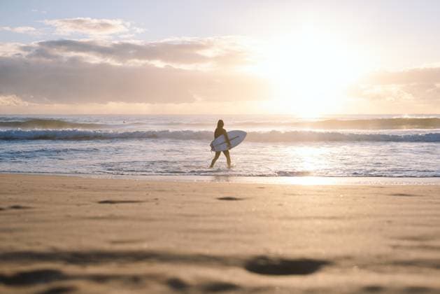 Creative Highlights Symbolbilder Surfer walking into ocean at sunrise on sandy manly beach Manly, New South Wales, Australia CR_MGTP250602-1738858-01 ,model released, Symbolfoto