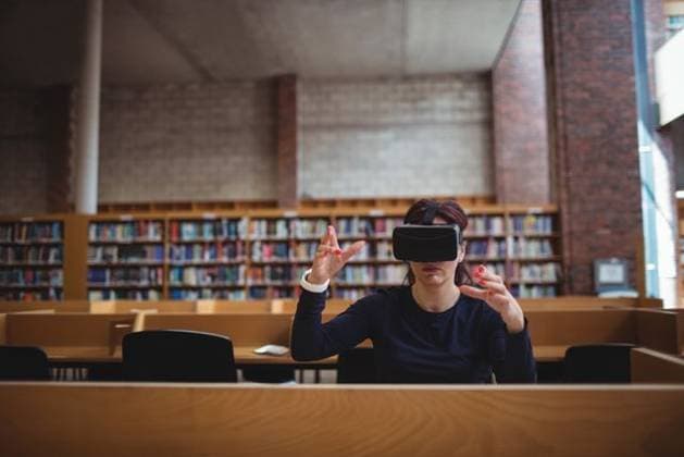 Creative Highlights Symbolbilder Woman is wearing virtual reality headset and raising hands at wooden desk in library reading room Woman is wearing virtual reality headset and raising hands at wooden desk in library reading room. Futuristic, immersive, education, technology, interior, innovative, knowledge, model released, , property released, , 13.06.2016, 6173440.jpg, virtual reality,headset,woman,hands,gesture,immersive,technology,education,knowledge,innovative,futuristic,library,reading room,wooden desk,study carrel,bookshelves,books,brick wall,concrete ceiling,interior,student,researcher,navy shirt,adult,female,white,seating,public,empty chairs,learning,digital,interface,manipulation,technology use,focused,interactive,modern,innovation,spacious,high ceiling,orderly,c
