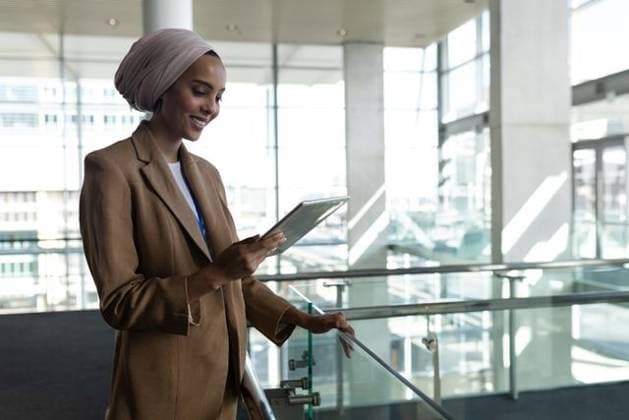 Creative Highlights Symbolbilder Businesswoman wearing tan blazer and hijab leaning on glass railing and using tablet in atrium Businesswoman wearing tan blazer and hijab leaning on glass railing and using tablet in atrium. Corporate, professionalism, modernity, architecture, technology, empowerment, collaboration, model released, , property released, , 17.11.2018, 6181979.jpg, businesswoman,tablet,hijab,corporate,professionalism,modernity,architecture,technology,empowerment,collaboration,tan blazer,middle eastern,female,adult,business professional,standing,leaning,glass railing,atrium,interior,modern,bright,natural light,floor-to-ceiling windows,structural columns,metal ceiling,lanyard badge,white shirt,interaction,reading,business,office,professional,confident,focus,wor