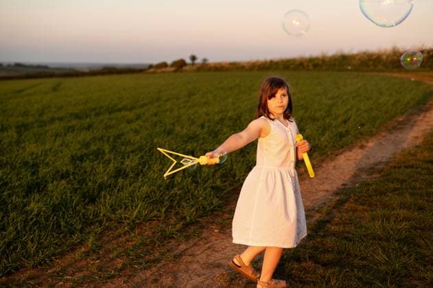 Creative Highlights Symbolfotos Girl watching at bubbles and holding bubble wand at sunset. Corby, England, United Kingdom R_JNDO250604-1738922-01 ,model released, Symbolfoto