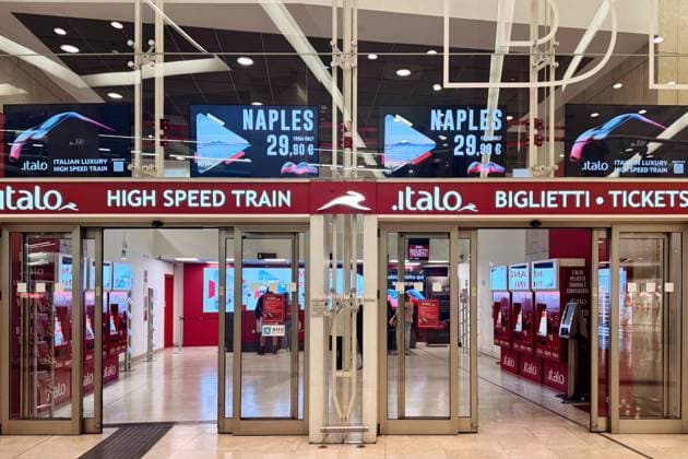 Mailand, Italien - 07. April 2025: Fahrkartenbereich des Italo-Zugs in Mailand. Rote Beschilderung mit Neapel-Werbung. Hochgeschwindigkeitsverkehr, digitale Bildschirme, Selbstbedienungskioske Milan, Italy - April, 07, 2025: Italo train ticket area in Milan. Red signage with Naples promotion. High-speed travel, digital screens, self-service kiosks. (License=RM) Copyright: xZoonar.com IgorxZakirovx 23462476