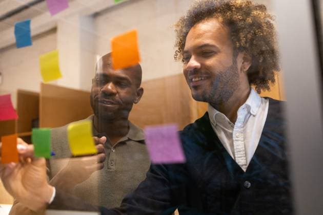 Professionals engage in a creative brainstorming session in a vibrant Barcelona coworking space, utilizing colorful sticky notes for visual organization and idea generation Model Released DavidMunoz_ID28576_843529_039 Copyright: xDavidxMunozx RECORD DATE NOT STATED