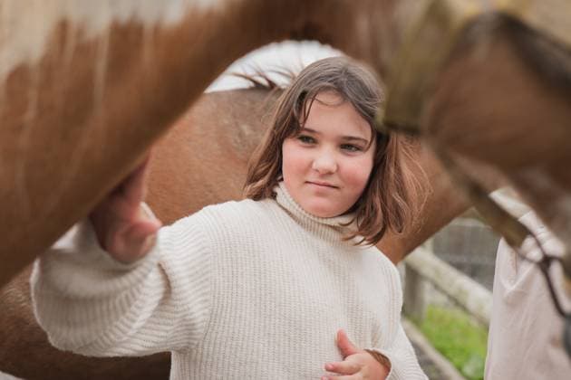 Creative Highlights Symbolfotos A young girl in a cozy sweater gently touches a horse on a sunny farm day. The scene captures the beauty of nature and the bond between the girl and the horse Model Released HodeiUnzueta_ID29195_895436_010 Copyright: xHodeixUnzuetax
