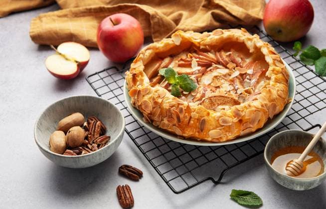 Freshly baked apple galette rests on a cooling rack, accompanied by honey, pecans, and fresh mint Model Released OlenaRudo_ID28805_850932_025 Copyright: xOlenaxRudox