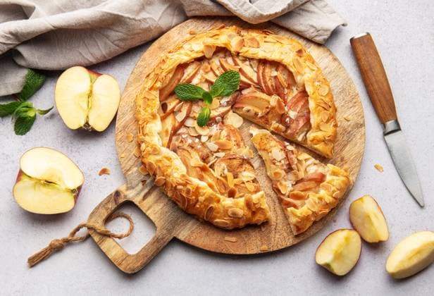 Freshly baked apple galette decorated with almond flakes and mint leaves, served on a wooden board Model Released OlenaRudo_ID28805_850967_046 Copyright: xOlenaxRudox
