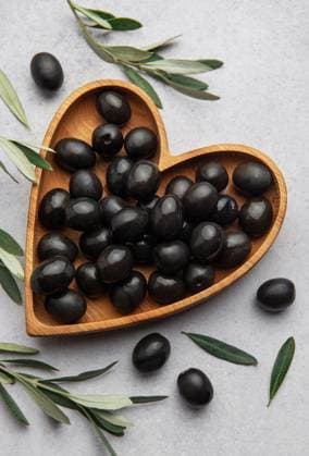 Fresh black olives in heart shaped wooden bowl on gray background with olive branches and copy space Model Released OlenaRudo_ID28871_858125_066 Copyright: xOlenaxRudox RECORD DATE NOT STATED