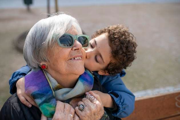 Creative Highlights Symbolfotos Grandchild sharing a loving moment with grandma Young grandchild affectionately kisses grandma on the cheek, showcasing the warmth and love in their family bond during a day at home Model Released GregorioReche_ID29817_1007593_012 Copyright: xx