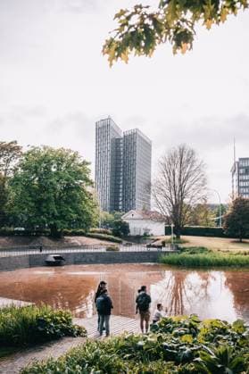 People by pond in urban park with modern skyscrapers in background. *** People by pond in urban park with modern skyscrapers in background 