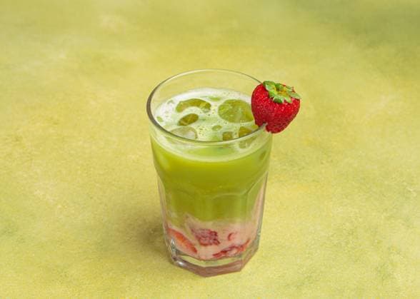 Geeister Matcha Latte mit Erdbeerpüree und Eiswürfeln, dekoriert mit frischen Erdbeeren in einem Glas auf grünem Hintergrund Refreshing iced matcha latte blended with strawberry puree and ice cubes, garnished with a fresh strawberry, served in a tall glass against a vibrant green background (License=RF) Copyright: xZoonar.com OlenaxYeromenkox 23566327