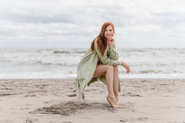 Creative Highlights Symbolbilder Redhead smiling woman 30 years old with long hair sitting on the beach Milano Marittima, Emilia-Romagna, Italy R_NEPM250412B-1312233-01 ,model released, Symbolfoto