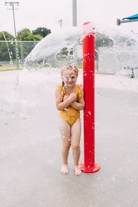 Creative Highlights Symbolbilder Child smiling under fountain at urban splash pad during summertime Jackson, Missouri, United States R_WEKW250611-1766204-01 ,model released, Symbolfoto