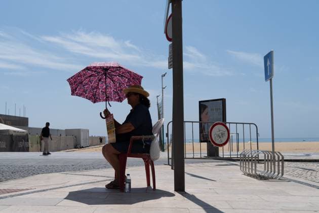 IMAGO Creative, Jahreszeit Sommer, Hitze June 17, 2025, Nazare, Santiago, Portugal: A woman shields herself from the sun with an umbrella on a hot day in Nazare, Portugal. Nazare Portugal - ZUMAb332 20250617_zip_b332_001 Copyright: xMatiasxBasualdox