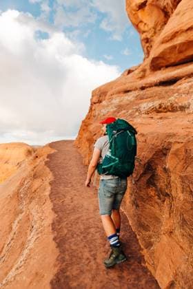Creative Highlights Symbolbilder Hiker with backpack walking red rock trail in Arches National Park Moab, Utah, United States CR_XPQF25061748-1735307-01 ,model released, Symbolfoto