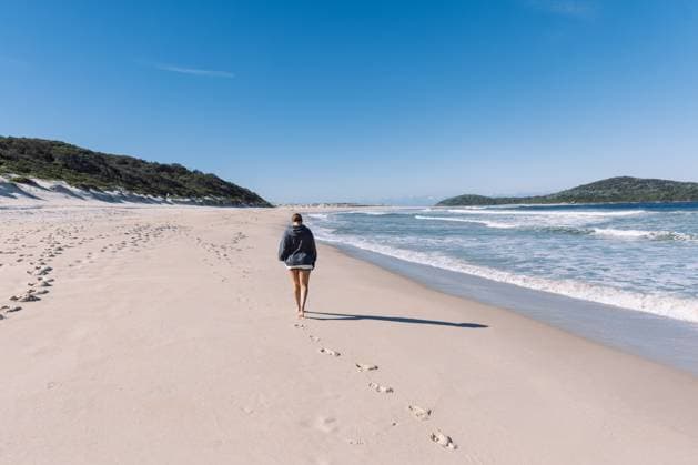 Tourist walking on the beach leaving footprints in the sand Fingal Bay, New South Wales, Australia CR_MGTP250620FD-1759707-01 ,model released, Symbolfoto
