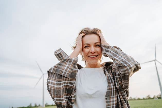 Creative Highlights Symbolbilder Smiling woman holding head in hand standing at field model released, Symbolfoto, MDOF02523