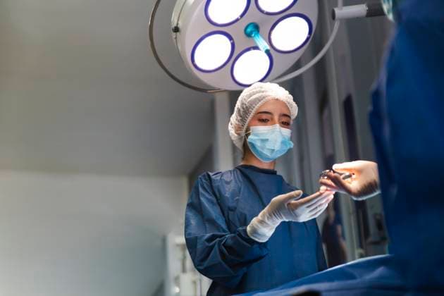 Nurse and doctor performing surgery in an operating room with surgical lights. model released, Symbolfoto property released, PCLF01993
