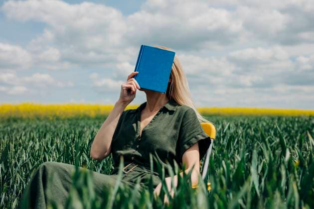 Creative Highlights Symbolbilder Woman sitting in a field with a book covering her face, enjoying a peaceful moment outdoors model released, Symbolfoto, VSNF03342