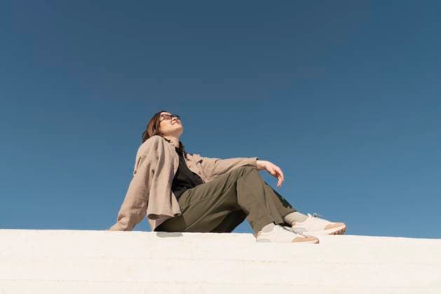 Creative Highlights Symbolbilder Woman sitting on steps outdoors under a clear blue sky, looking relaxed and fashionable model released, Symbolfoto, VPIF09759
